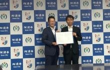 加須市高橋稔裕市長と株式会社埼玉りそな銀行平野隆司執行役員埼玉東地域営業本部長とが協定式で協定締結を記念して協定書を掲げる様子