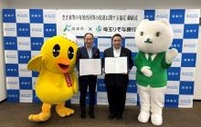 鴻巣市並木正年市長と株式会社埼玉りそな銀行石井良輔執行役員埼玉県央・北地域営業本部長が両者のマスコットキャラクターと、協定式で協定締結を記念して協定書を掲げる様子