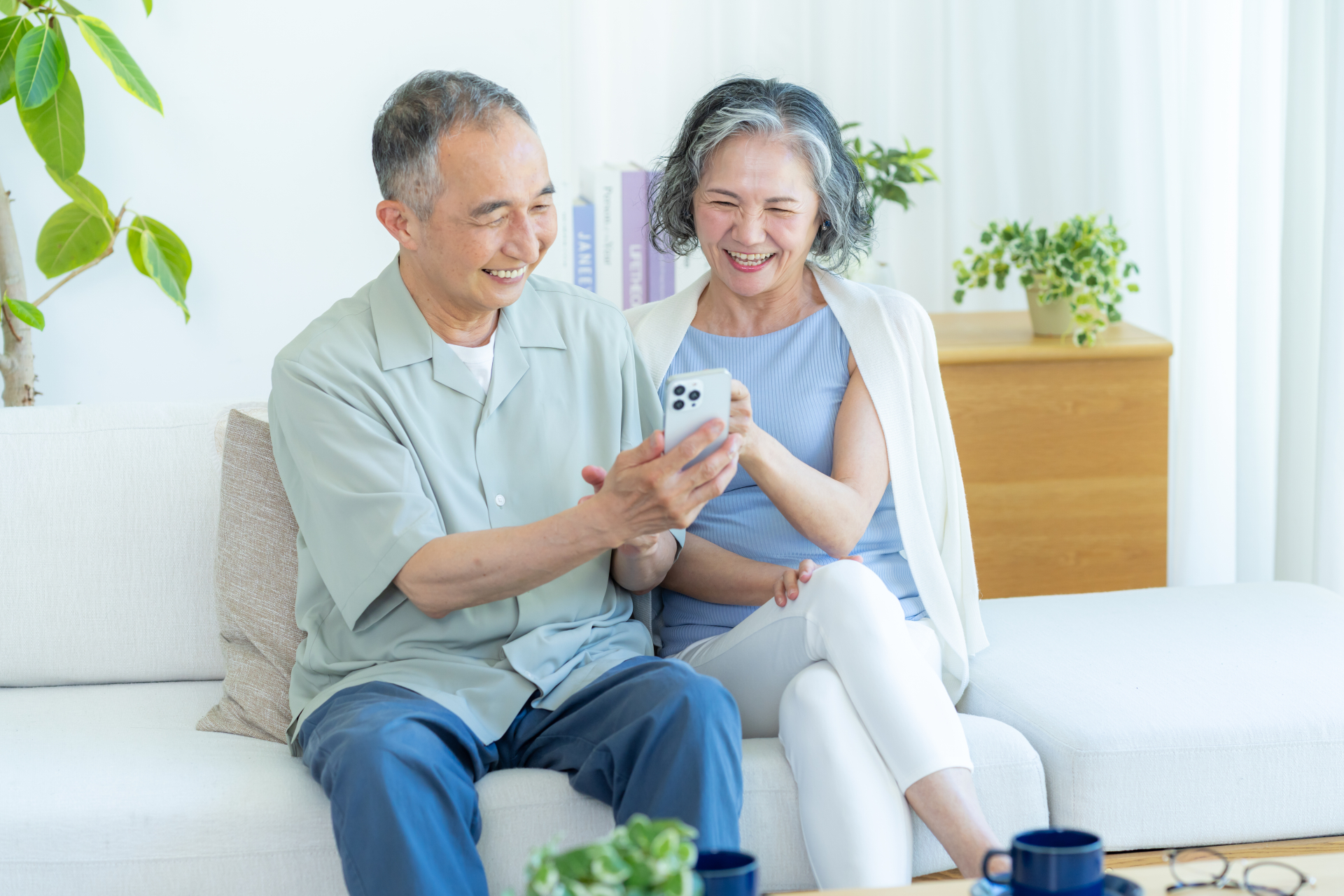 ソファに座り、スマートフォンの画面を一緒に見ながら活用方法を確認している2人の様子