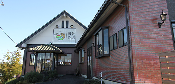 赤レンガ調の外壁の建物と、入口付近に掲げられた「国分牧場」の看板。