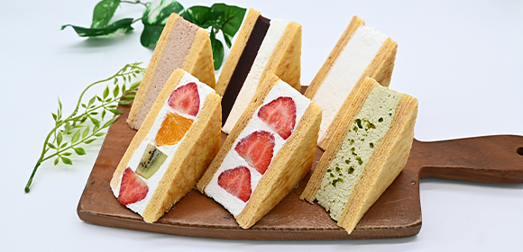 木製のボードに、クリームや果物を挟んだ三角形の焼き菓子が複数並んでいる。